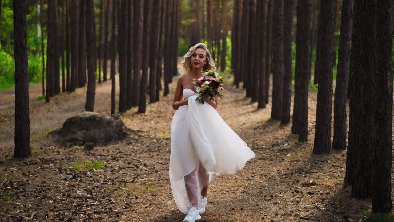 Sposa con acconciatura e il bouquet corre e si gira nel bosco.