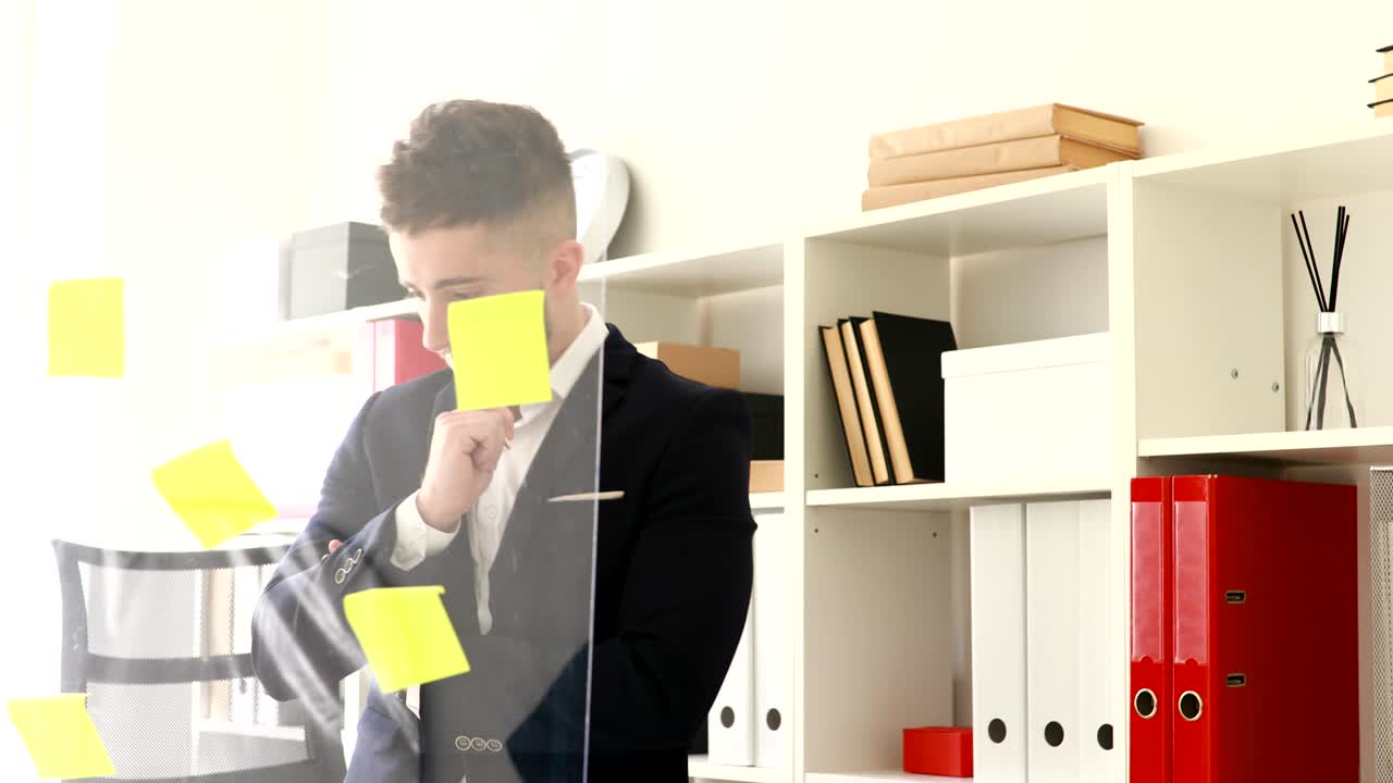 hombre de negocios en traje quitando pegatinas de la pared de vidrio
