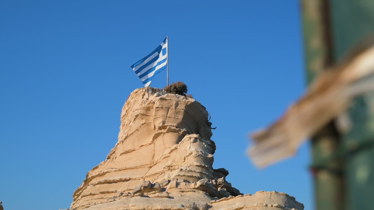 revelación de la bandera nacional de grecia montada en la cima de una meseta rocosa