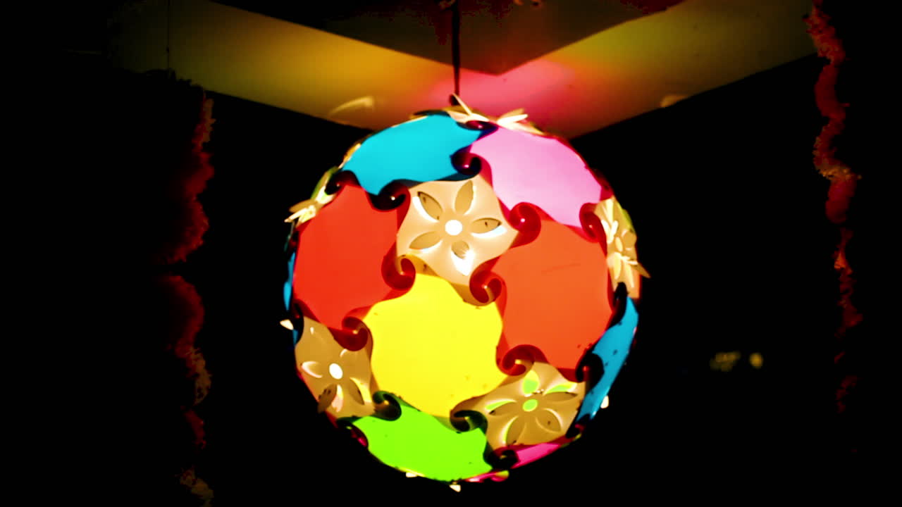 Colorful hanging lamp glowing bright at night during Indian festival. Decorative handmade light ball adds warm festive mood perfect for Diwali, celebration, or holiday decor background