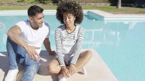 Young-couple-relaxing-in-the-sun-at-a-pool