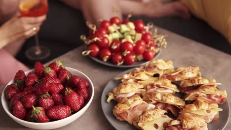 women's party with cocktails. girls communicate with each other, smiling and gossip sitting on the sofa in the room. aim footage of table with some appetizer