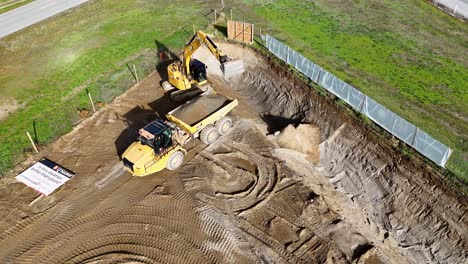 excavator and dump truck operate on a sunny day, moving earth at a construction site in cromwell, new zealand