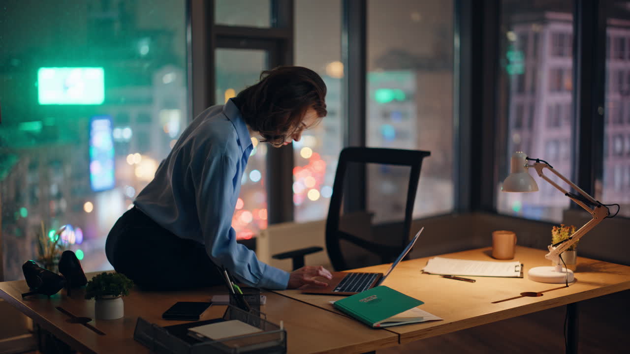 Imprenditore che lavora a un progetto fino a tarda sera, mentre consulta un'applicazione sul laptop