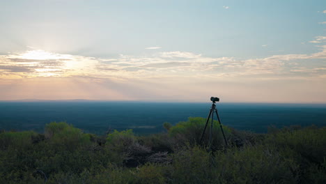 camera on a tripod capturing a sunset over a vast landscape