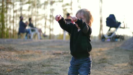 Little-boy-pointing-around-and-playing-in-a-finnish-forest,-on-a-sunny-spring-day,-in-Vaasa,-Ostrobothnia,-Finland