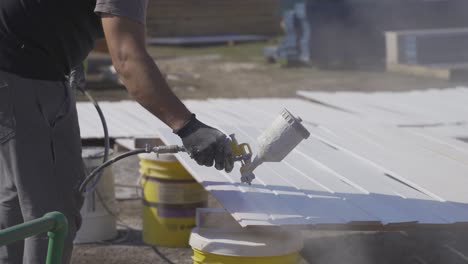 Close-up-of-white-paint-sprayer-on-wooden-planks