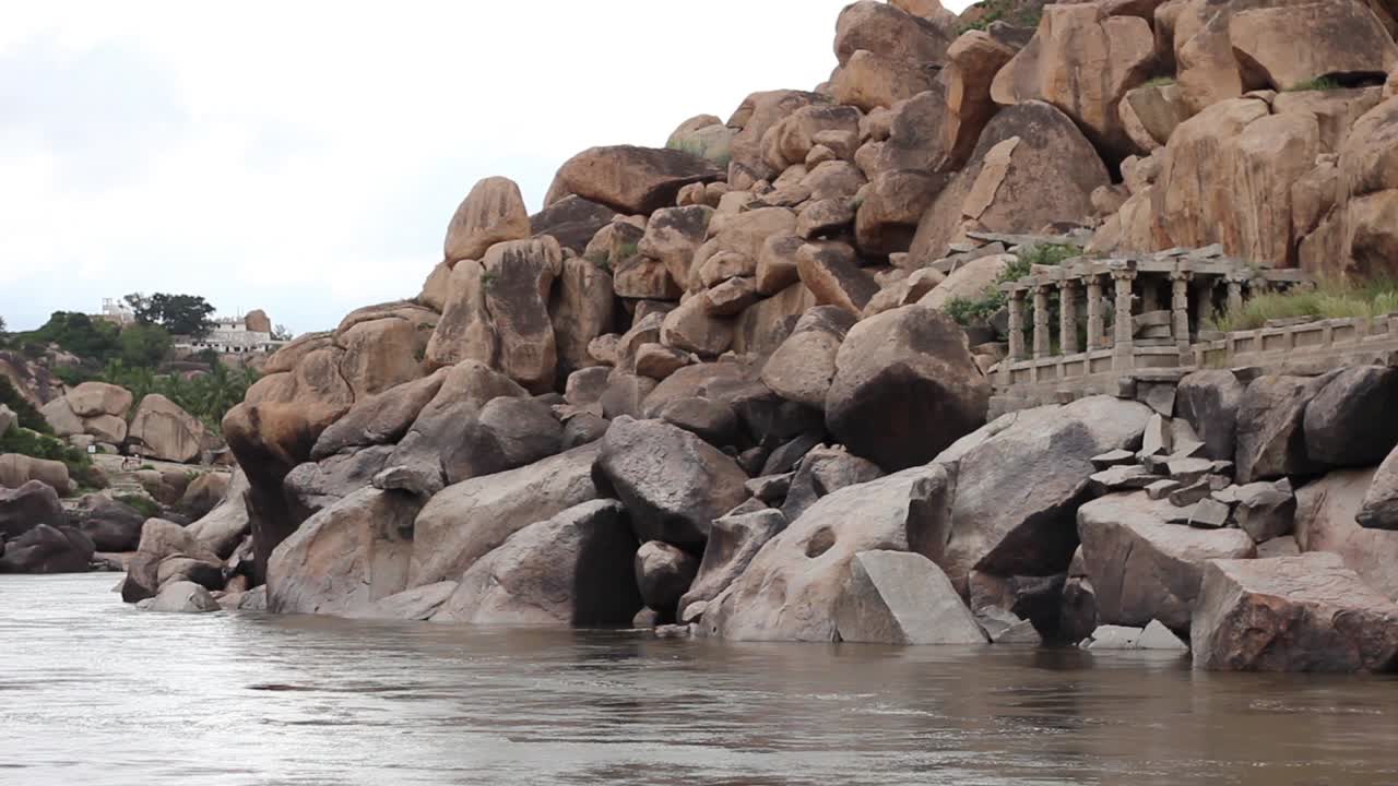 Long shot of ancient ruins and boulders by the Tungabhadra River in Hampi