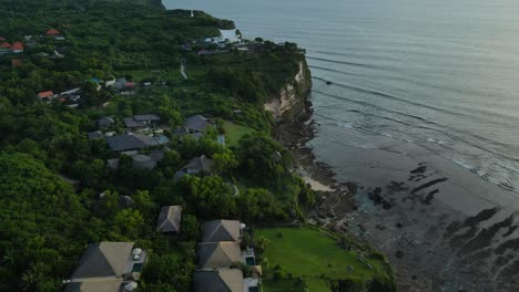 drone shot of clifftop villas and buildings on coastline of bali island, indonesia