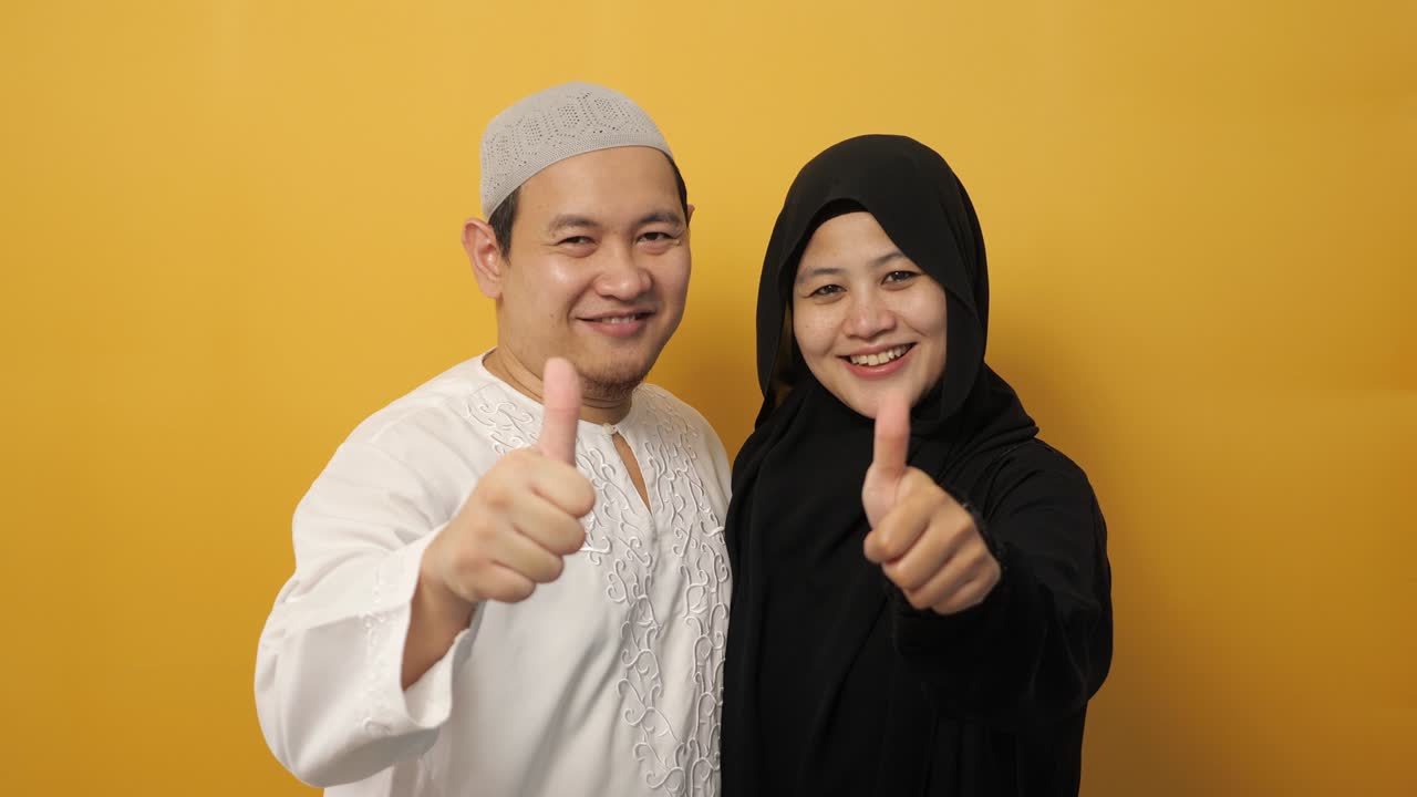 retrato de una feliz pareja musulmana asiática sonriendo y mostrando el pulgar hacia arriba gesto, marido y mujer abrazándose llenos de amor, familia
