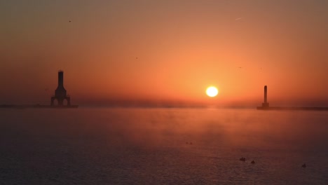 a beautiful sunrise on lake michigan featuring a lighthouse and breakwater