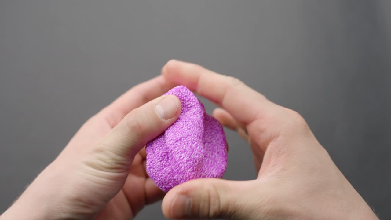 Hands squeeze purple Floam slime, showing texture in a stress-relief moment