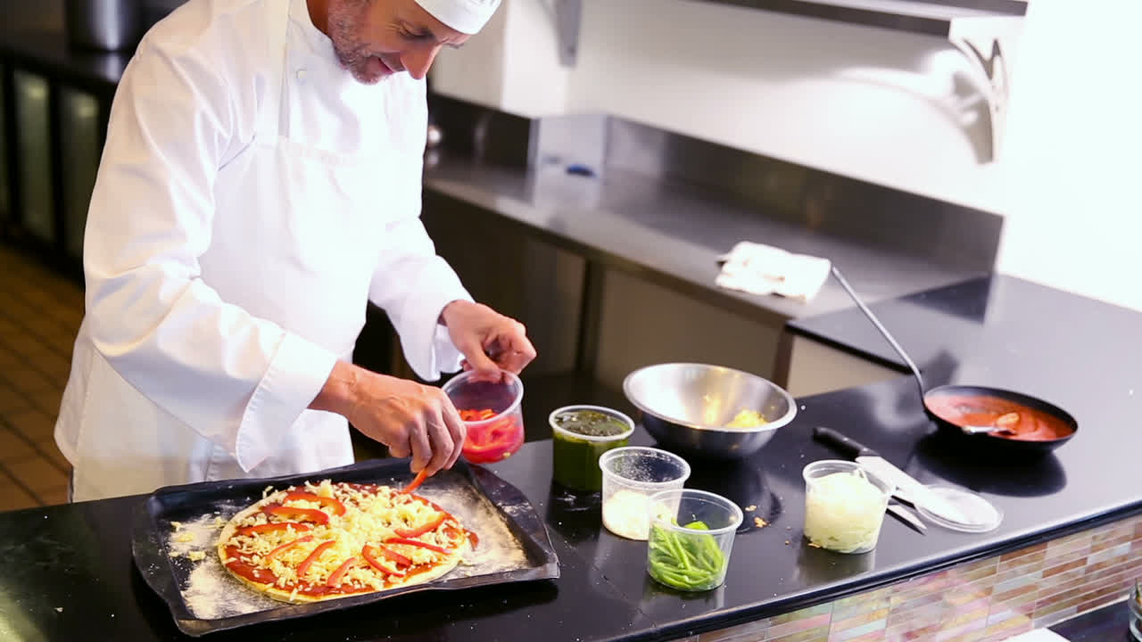 el chef salpicando pimientos en una pizza
