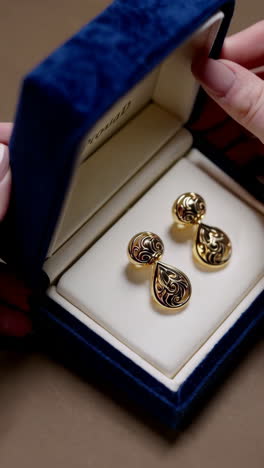 gold drop earrings in a blue velvet box