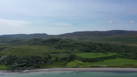 aerial shot rising over the coastline on the island of islay, showing beautiful green hills and countryside