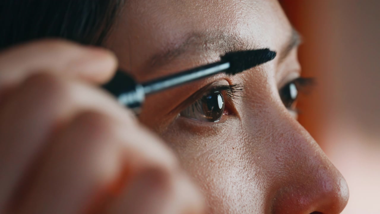 Macro woman applying mascara eyelashes. Close up eye makeup beauty routine.