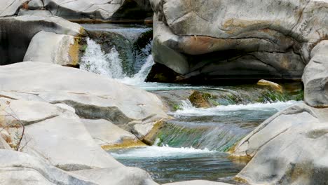 waterfalls cascading over rocks in forest landscape with mountains and blue sky