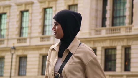 Muslim-Businesswoman-Wearing-Hijab-With-Modern-Business-Suit-Walking-To-Work-Past-City-Office-Buildings-1