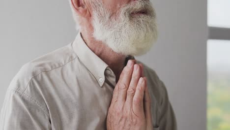 deeply religious bearded man praying god, whispering his wishes folding hands