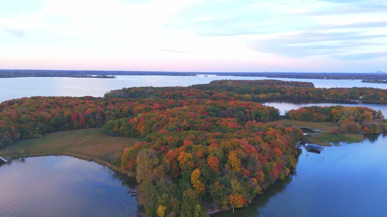 A tranquil autumn afternoon over Lake Minnetonka showcases colorful foliage reflecting on calm waters