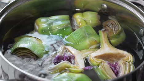 y cocinar alcachofas en una sartén, de cerca en la cocina