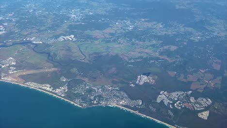 very high aerial view over the sunshine coast in the state of queensland in australia, with long sandy beaches and vibrant beachside communities, patchwork fields and a snaking river