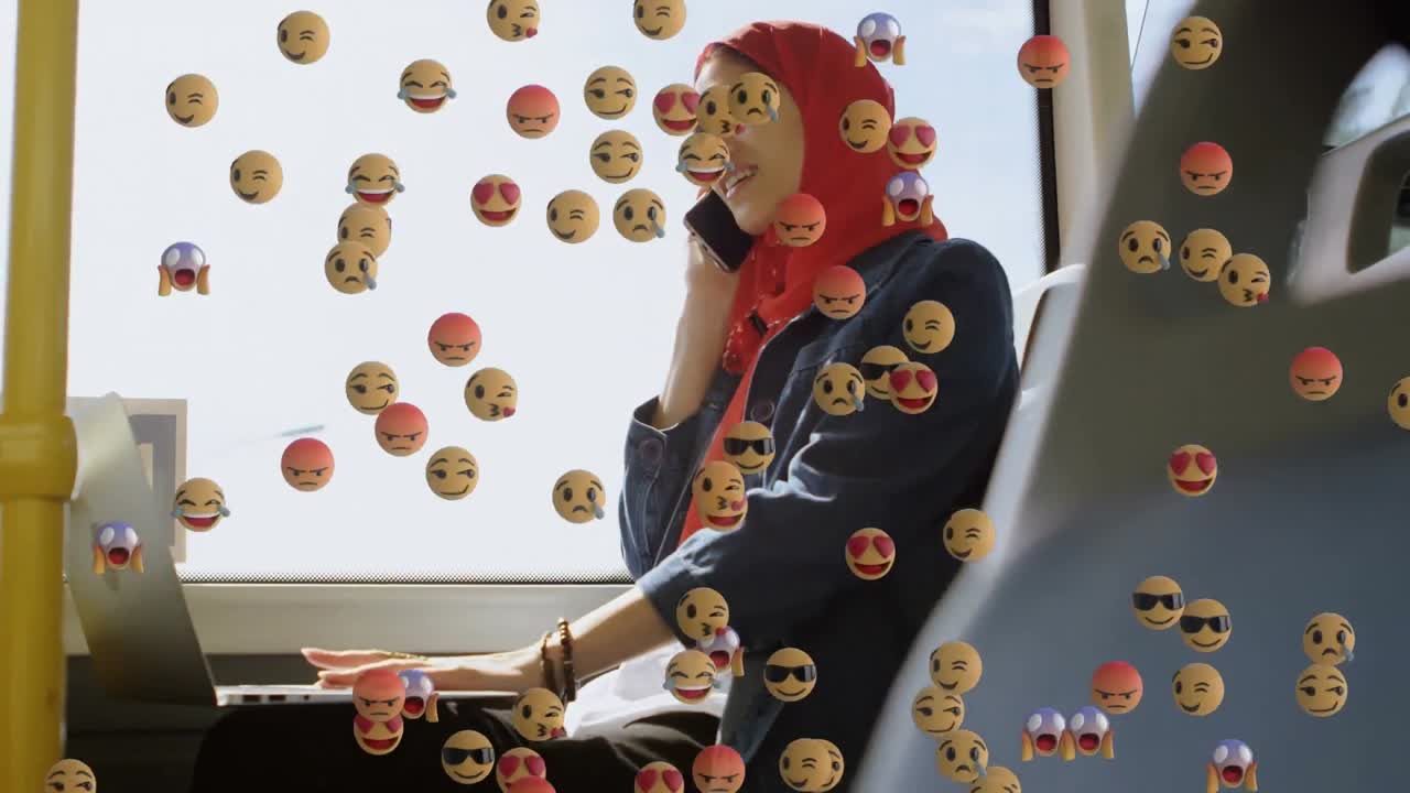 анимация падающих эмодзи над женщиной в хиджабе с помощью смартфона