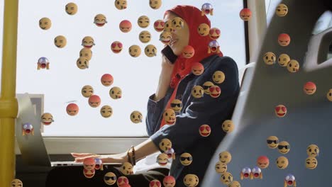 animación de emojis que caen sobre una mujer con hijab usando un teléfono inteligente