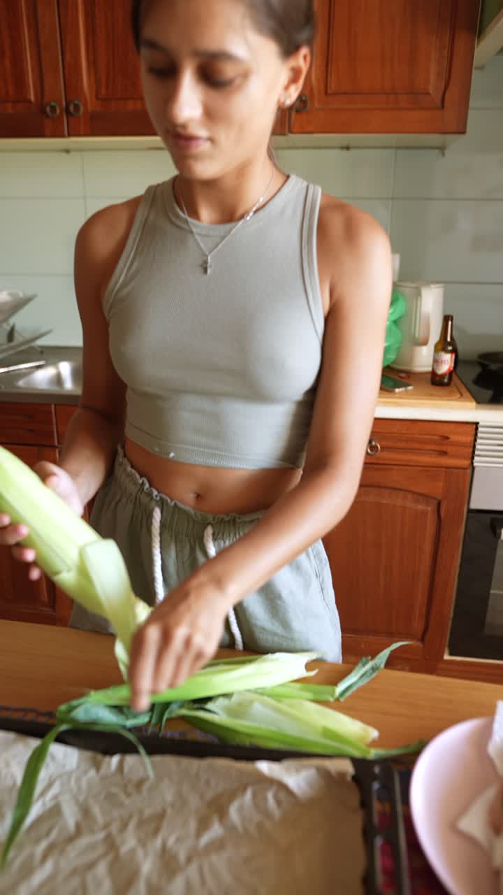 Woman peeling corn in the kitchen