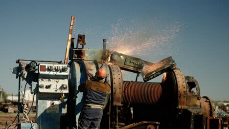 metal torcher working on a big piece of machinery