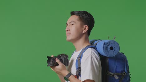 man with camera and backpack on green screen