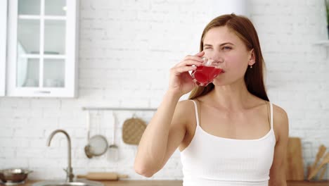 the girl takes a glass of freshly squeezed fruit juice and drinks with pleasure