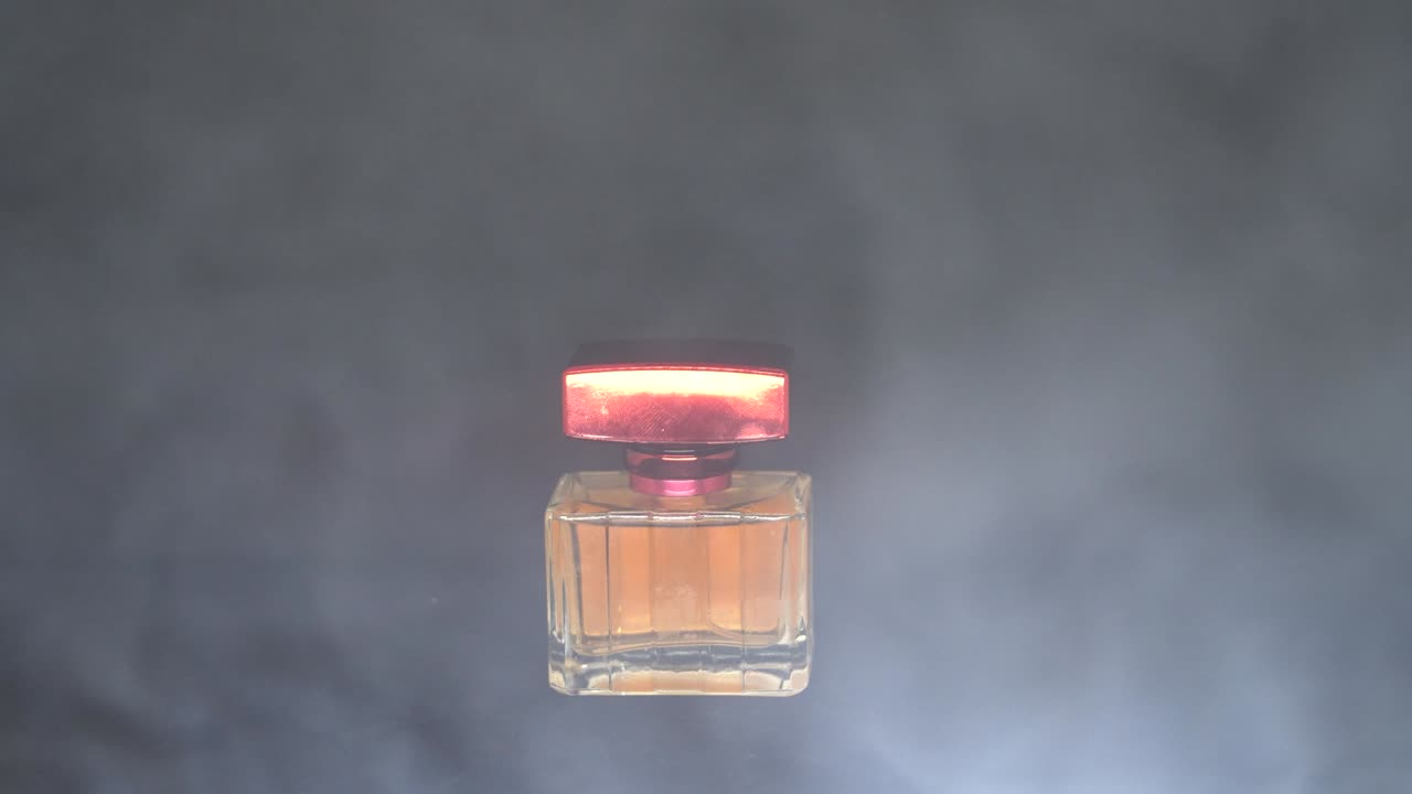 botella de perfume con líquido naranja. efecto de humo. fondo negro