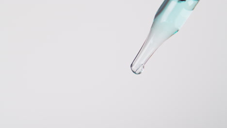 a bluish liquid flowing from a transparent pipette, close shot