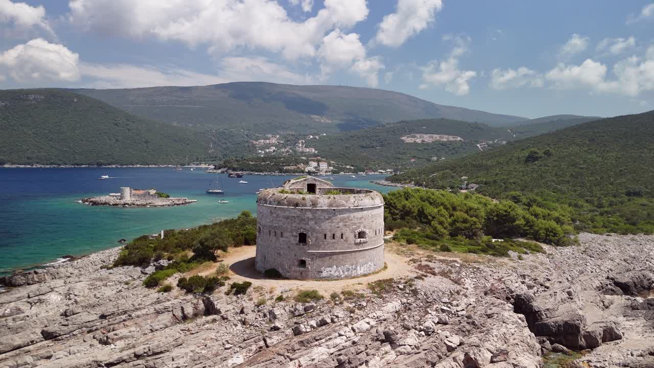 Low aerial approaches Arza fortress on rocky headland, Montenegro