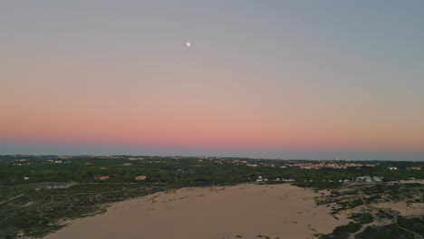 drone view dusk town under tranquil twilight sky with moon presiding over.