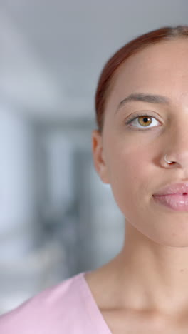 vertical video of portrait of biracial female doctor with nose piercing, smiling, slow motion