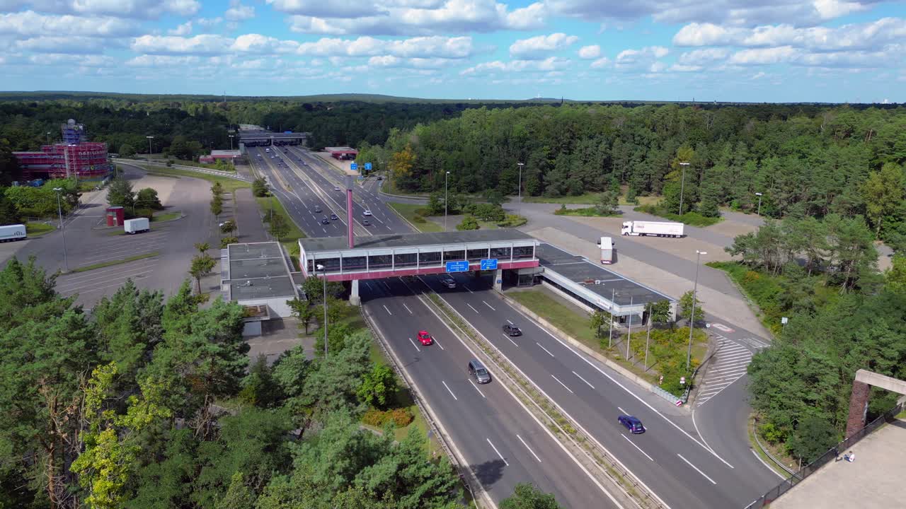 Dreilinden Checkpoint Bravo border crossing. German freeway traffic on sunny day with blue sky. Amazing aerial view flight panorama orbit drone