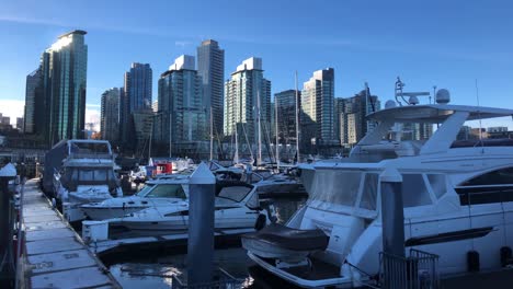 luxury pleasure yachts moored at frozen jetty's on a cold sunny winter day with skyscrapers build with glass on the background