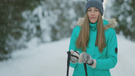 Waist-up-portrait-of-beautiful-young-woman-smiling-happily-looking-at-camera-while-enjoying-skiing-in-snowy-winter-forest,-copy-space