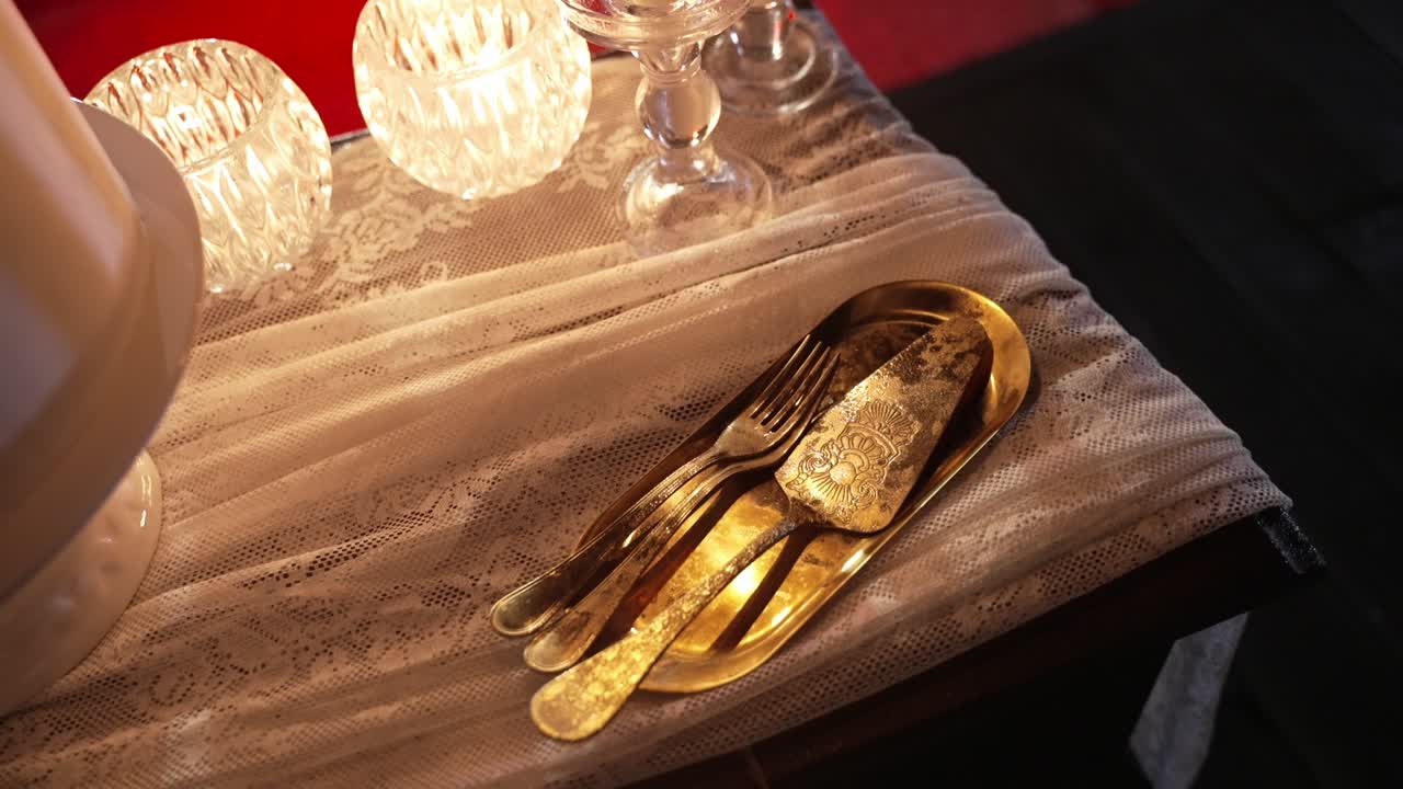 elegant gold utensils, including forks and a cake server, placed on a lace-draped table, illuminated with soft light, creating a warm and sophisticated ambiance