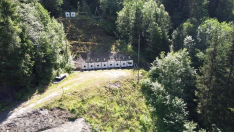 Objetivos-En-El-Campo-De-Tiro-Al-Aire-Libre-Cerca-Del-Río-Strandaelvi-En-Voss-Noruega---Antena-De-Día-Soleado-Moviéndose-Hacia-Atrás-Desde-Los-Objetivos