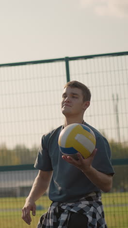 hombre durante la sesión de entrenamiento de voleibol lanza la pelota a alguien en el fondo, la atrapa de vuelta con la dama con la capucha cian mirando y otra mujer observando, trabajo en equipo y atmósfera de entrenamiento