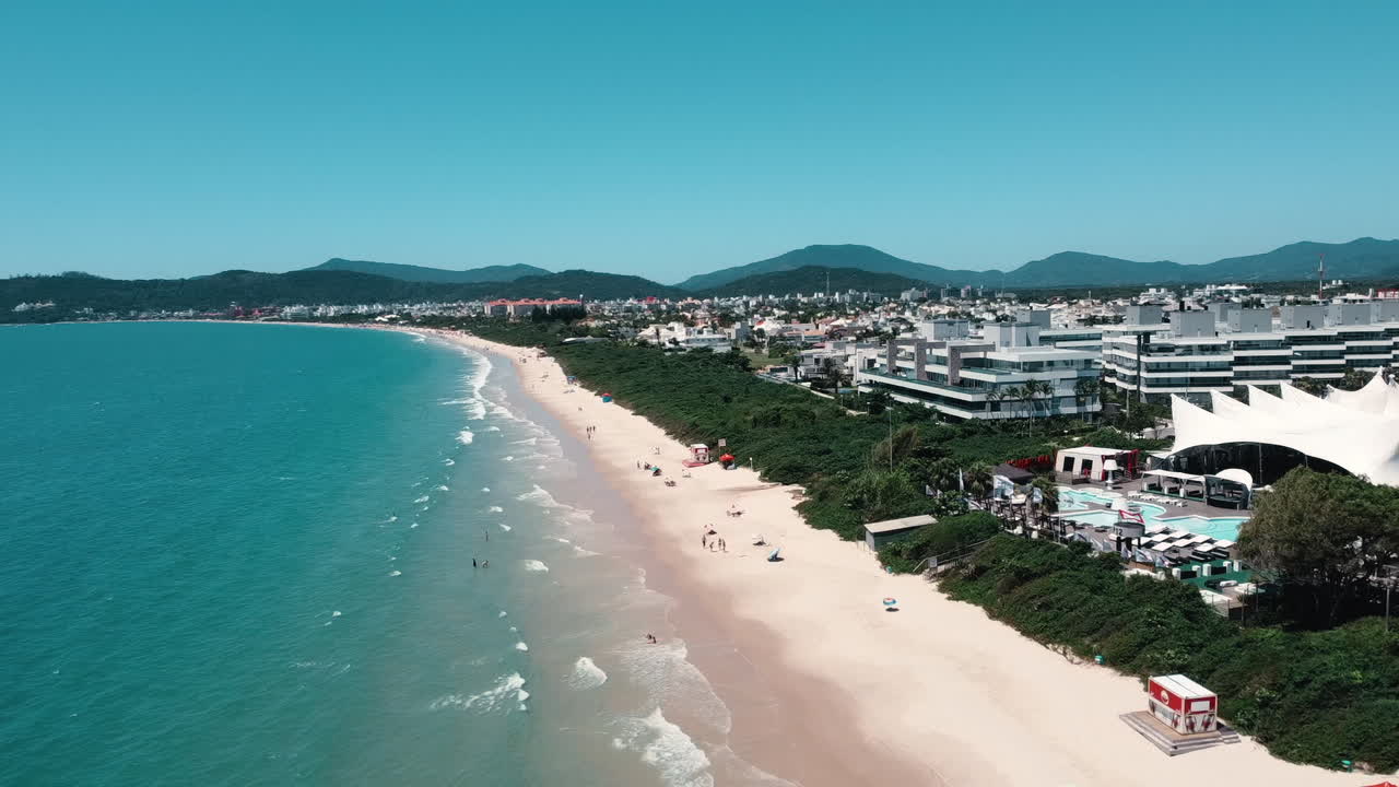 A comprehensive lateral drone view capturing the entire shoreline of Jurer&ecirc; Internacional Beach, Florian&oacute;polis