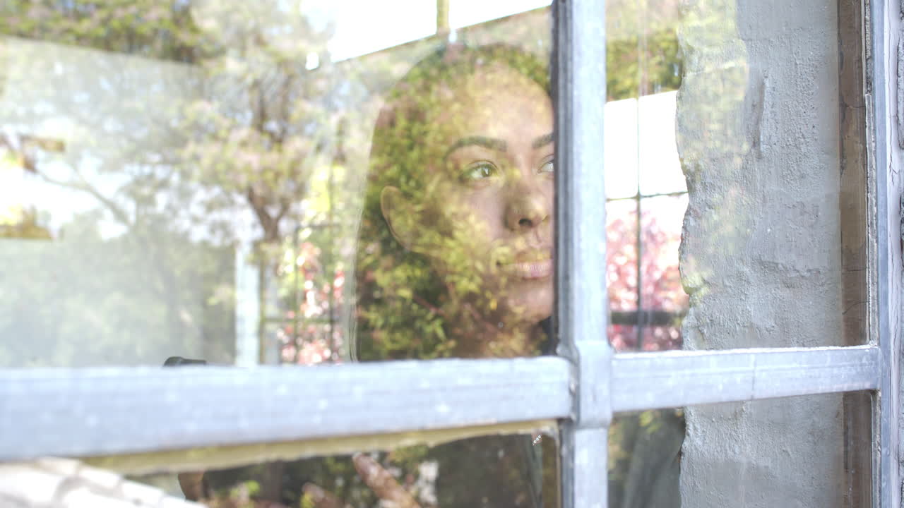 Gazing thoughtfully out window, woman reflecting on autumn day indoors, at home office