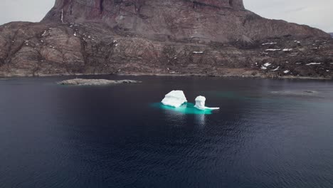 melting iceberg in the arctic, showcasing climate changes and global warming - tilt shot