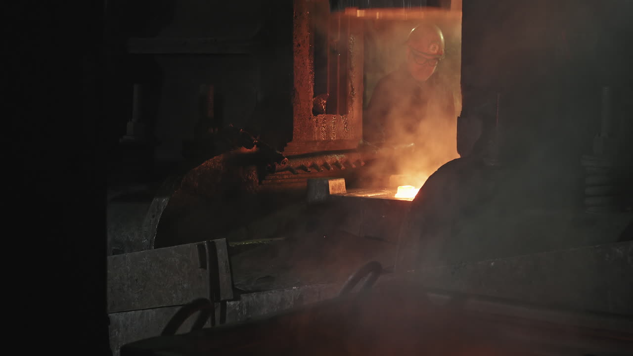 Black Smith Holding Hot Steel At Hydraulic Press