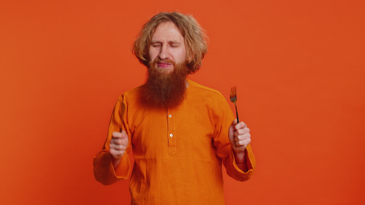 ⁇ 주린 남자가 저녁 식사를 위해 기다리고 있습니다. 불안함으로 식사 접시를 들고 식기 포크 칼을 들고 있습니다.