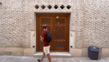 Step-into-History:-4K-Static-View-of-a-Young-Man-Emerging-from-a-Traditional-Wooden-Door-in-Historic-Bukhara-Old-Town,-Uzbekistan