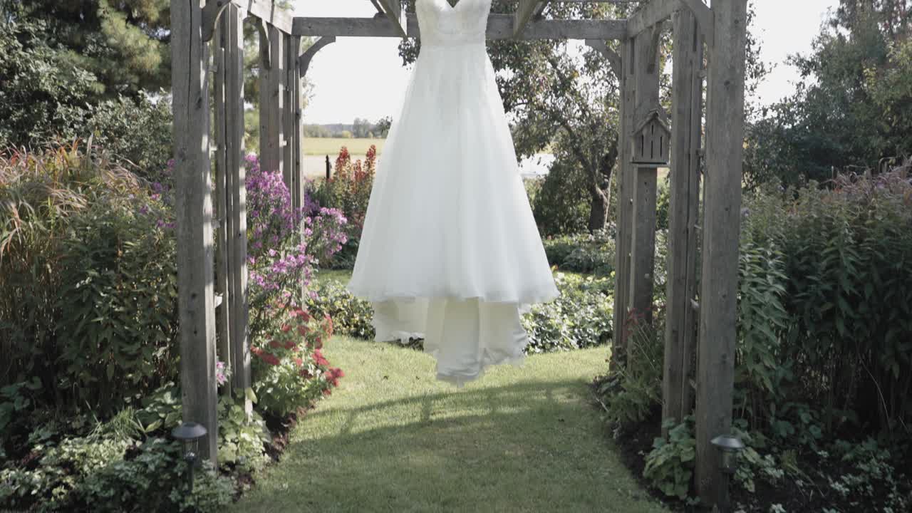 오타와의 스트라스미어 리조트 정원에 있는 녹청색 목재 퍼걸러에 매달려 있는 웨딩드레스의 아름다운 모습